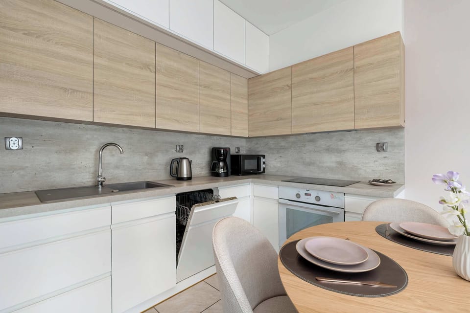 This view of the kitchen emphasizes the clean lines of the cabinetry and the integrated appliances. The space is well-organized, featuring a built-in oven and a stainless steel sink.