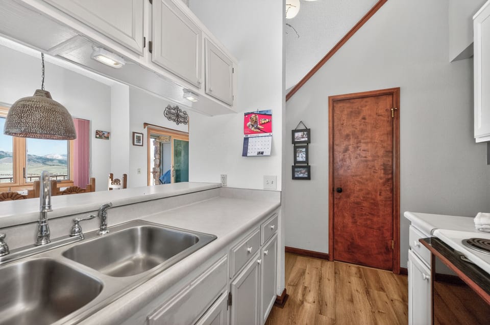 Your fully equipped kitchen features gleaming countertops, double sink, and everything you need to prepare meals while enjoying mountain views through the window.