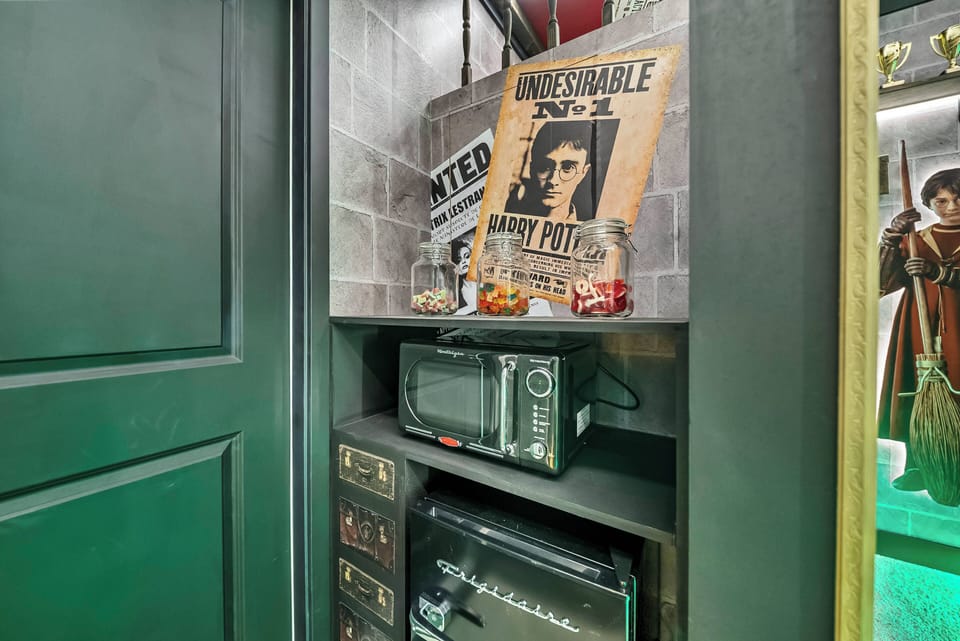 Explore the charm of this cozy nook, where rich green cabinetry complements a compact microwave and retro decor. Vintage posters add a unique touch, blending functionality with character for a delightful experience.