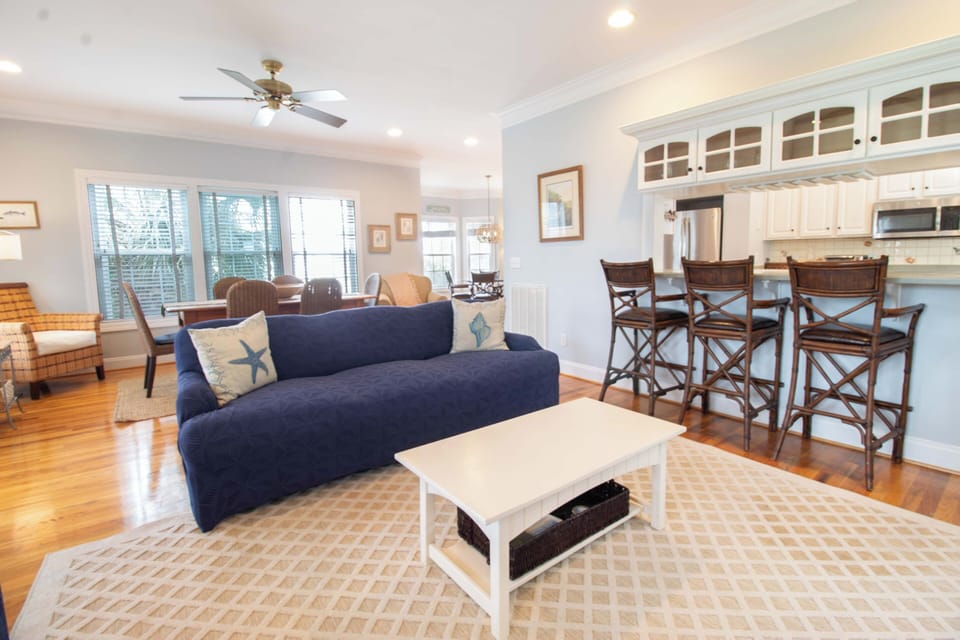 Relax in your bright open living space with navy sofa, breakfast bar seating, and coastal touches throughout.
