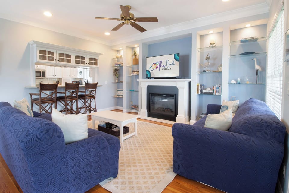 Sink into plush blue chairs while the fireplace warms your evening. Your open-concept living space flows seamlessly to the kitchen.