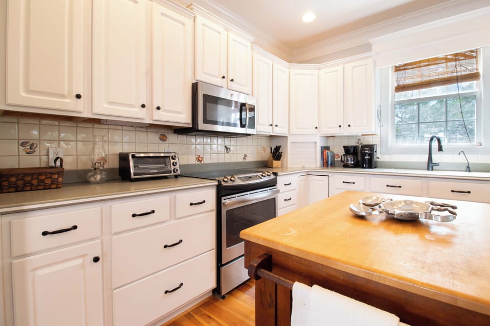 Cook memorable meals in your well-equipped kitchen featuring white cabinets, stainless appliances, and a warm wooden island for gathering.