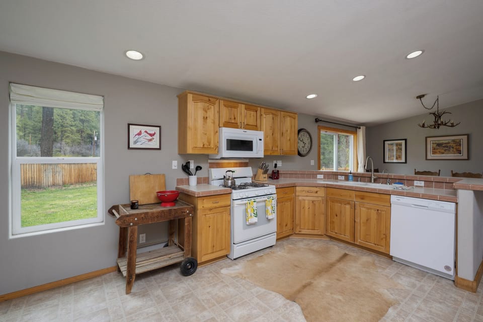 Your spacious kitchen features warm wood cabinetry, modern appliances, and large windows offering peaceful garden views—perfect for preparing home-cooked meals during your stay.