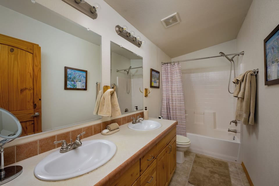 Your spacious bathroom features dual sinks with warm wood cabinetry, a full tub-shower combo, and cozy towels—perfect for unwinding after a day of adventure.