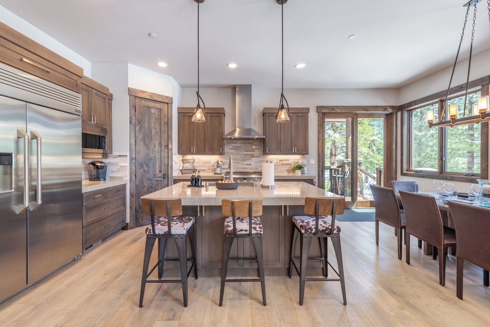 Your gourmet kitchen awaits with sleek appliances, spacious island seating, and warm wood finishes perfect for cooking memorable meals together.