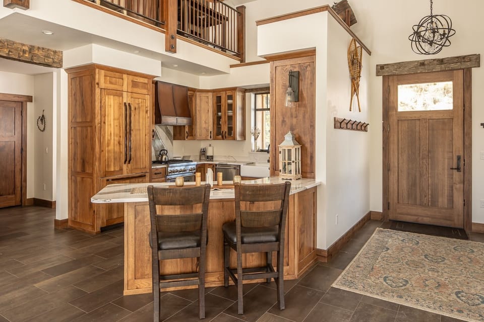 Your rustic mountain kitchen welcomes with warm wood cabinetry, granite counters, and breakfast bar seating.