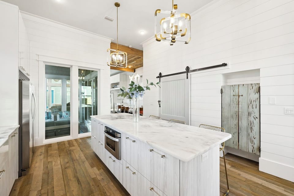 Step into your dream kitchen featuring marble countertops, gleaming white cabinets, and warm wood floors under stunning pendant lighting.