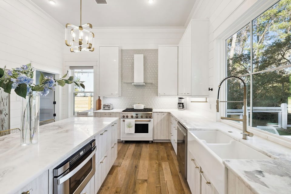 Step into this bright, spacious kitchen where you'll love preparing meals on pristine marble counters with garden views streaming through large windows.