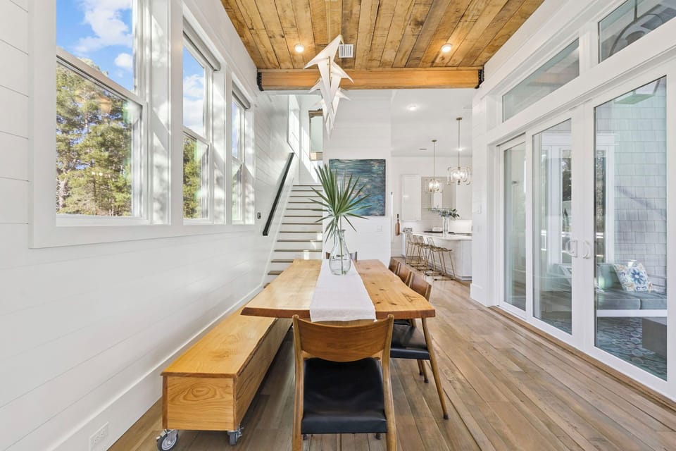 You'll love gathering around this stunning live-edge dining table beneath soaring wood beam ceilings in this bright, modern space.