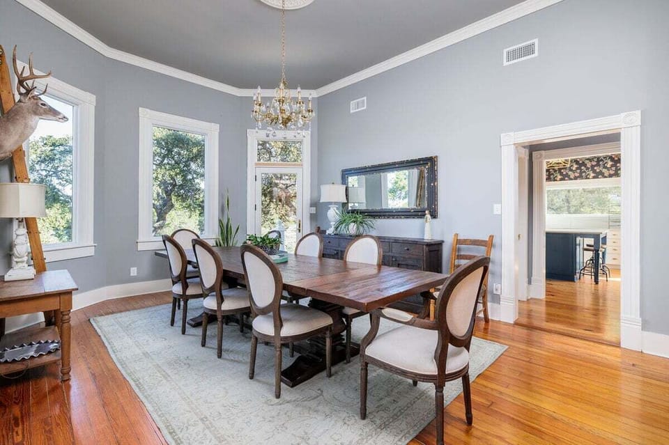 Bask in the warm glow of natural light as you dine in this inviting space, where the wooden table comfortably seats up to 8 guests, fostering moments of togetherness and shared meals