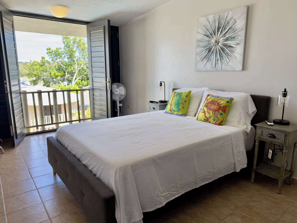 Bright bedroom with balcony access and a refreshing tropical view.
