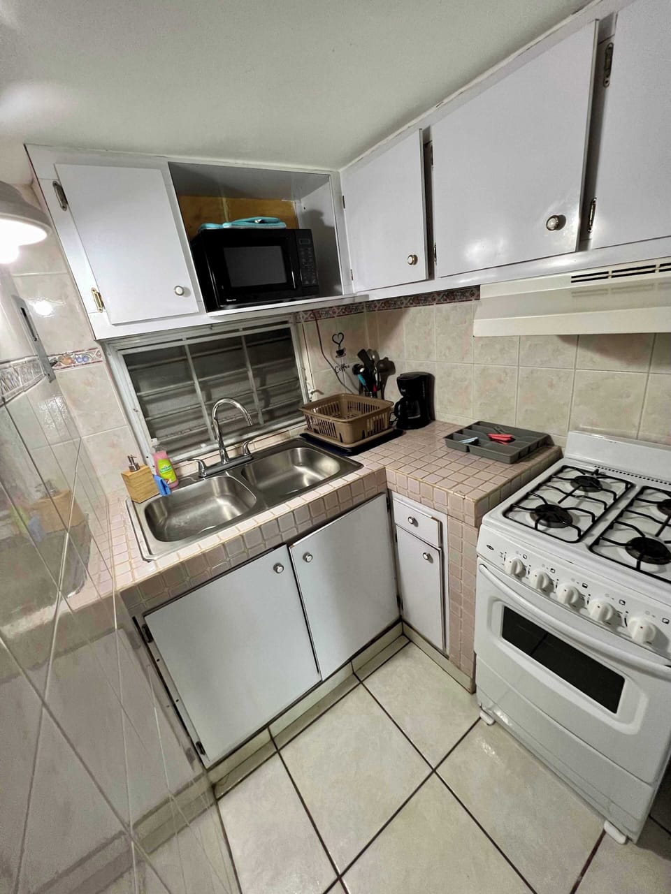 Fully equipped compact kitchen with gas stove, microwave, and ample cabinet space.
