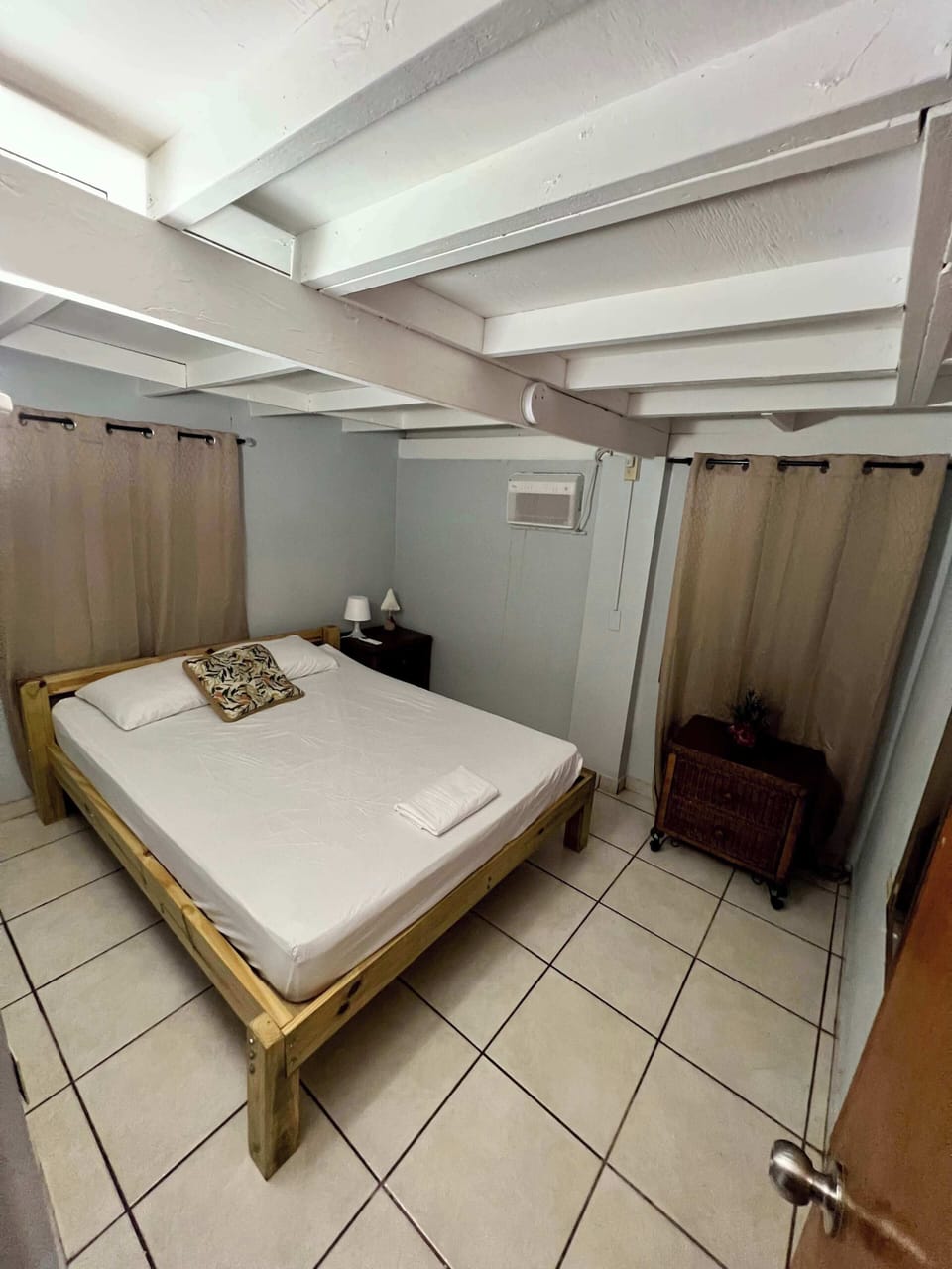 Comfortable bedroom with wooden bed frame, air conditioning, and curtain dividers.