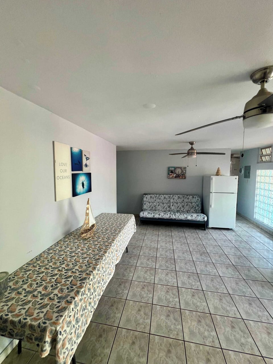 Casual living and dining space with ceiling fans, and a sofa bed.