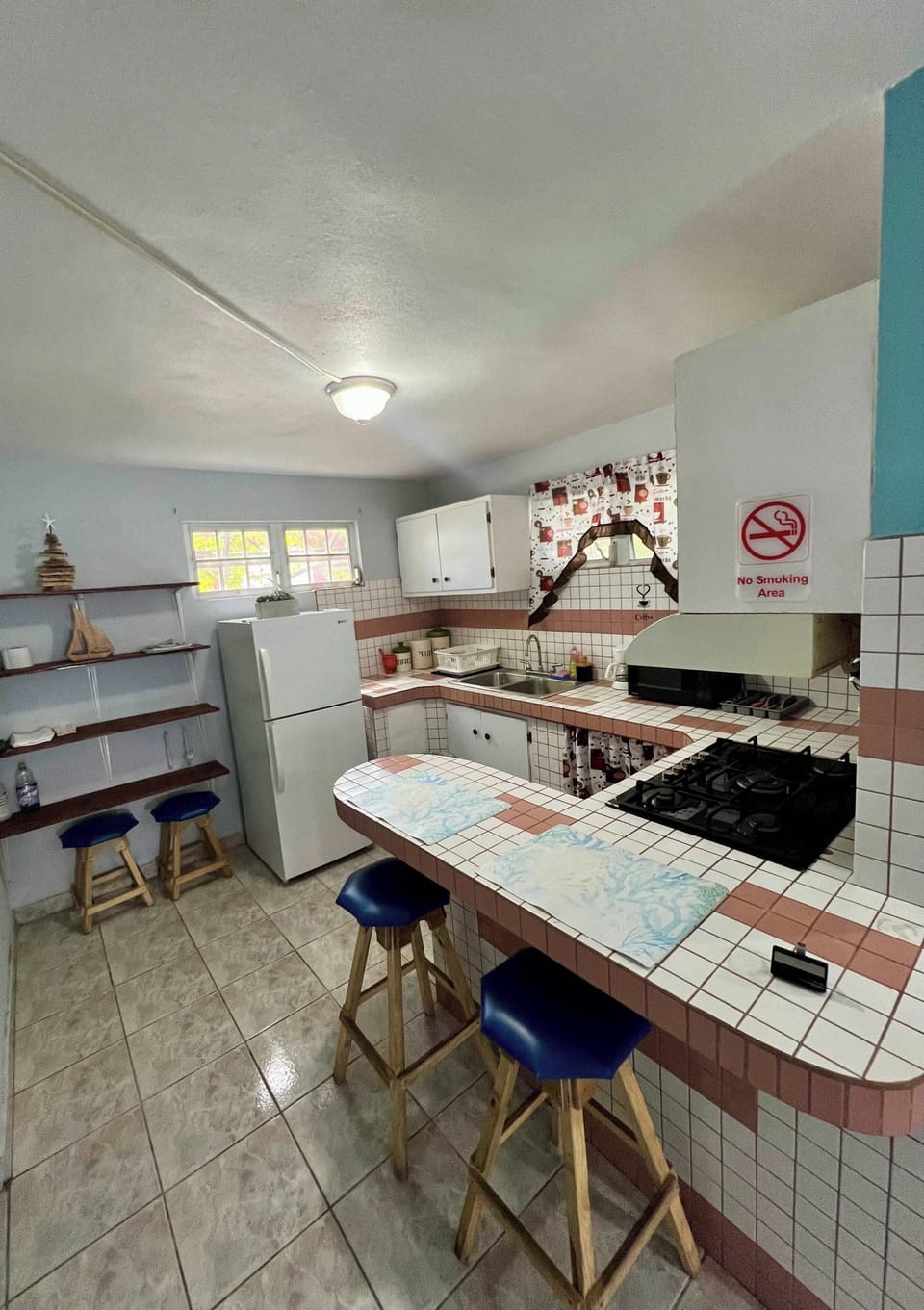 Kitchen with tiled counters, bar seating, and full appliances.
