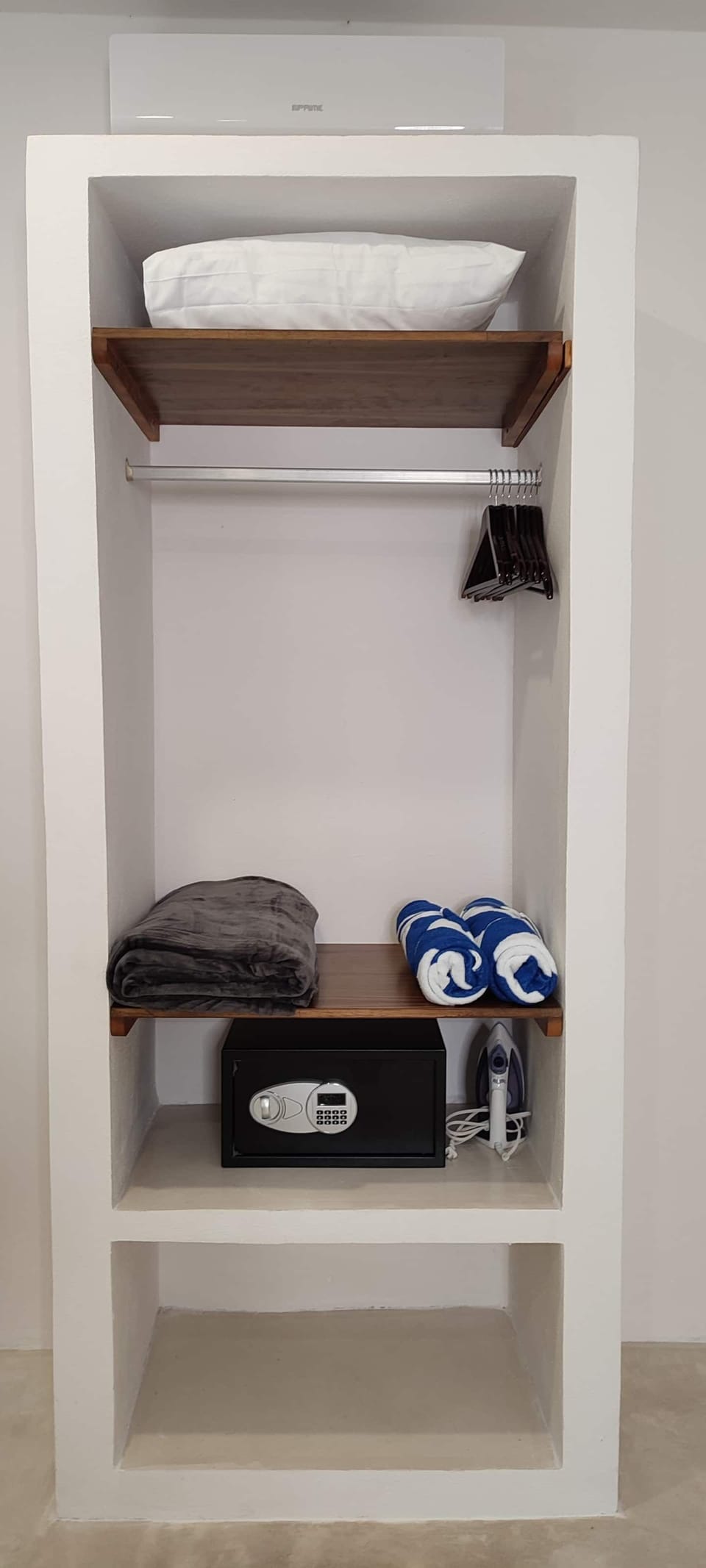 Closet includes a safe box, extra pillow and grey blanket, beach towels and an iron.