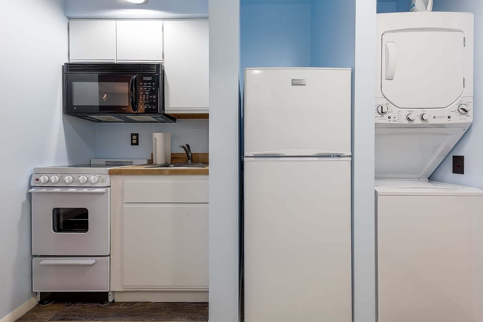 A petite kitchenette featuring a microwave, refrigerator, and a washer & dryer.