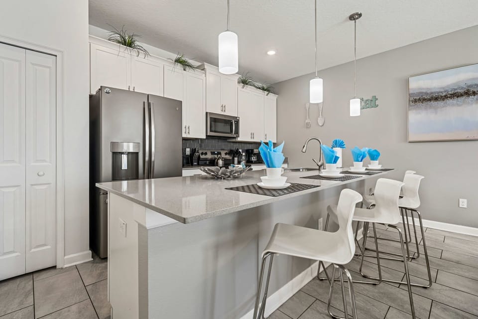 Cook and snack with ease in this modern kitchen, featuring stainless appliances, a roomy breakfast bar, and cheerful blue accents.