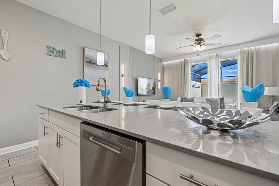 Enjoy a spacious, light-filled kitchen and lounge area with quartz countertops, a large island, modern decor, and relaxing views to the screened patio.