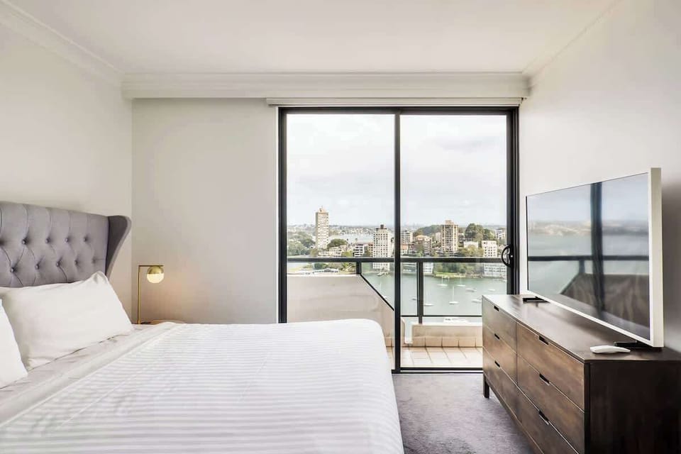 Large bedroom with new king size bed, frame TV and built in robe with wooden coat hangers. 