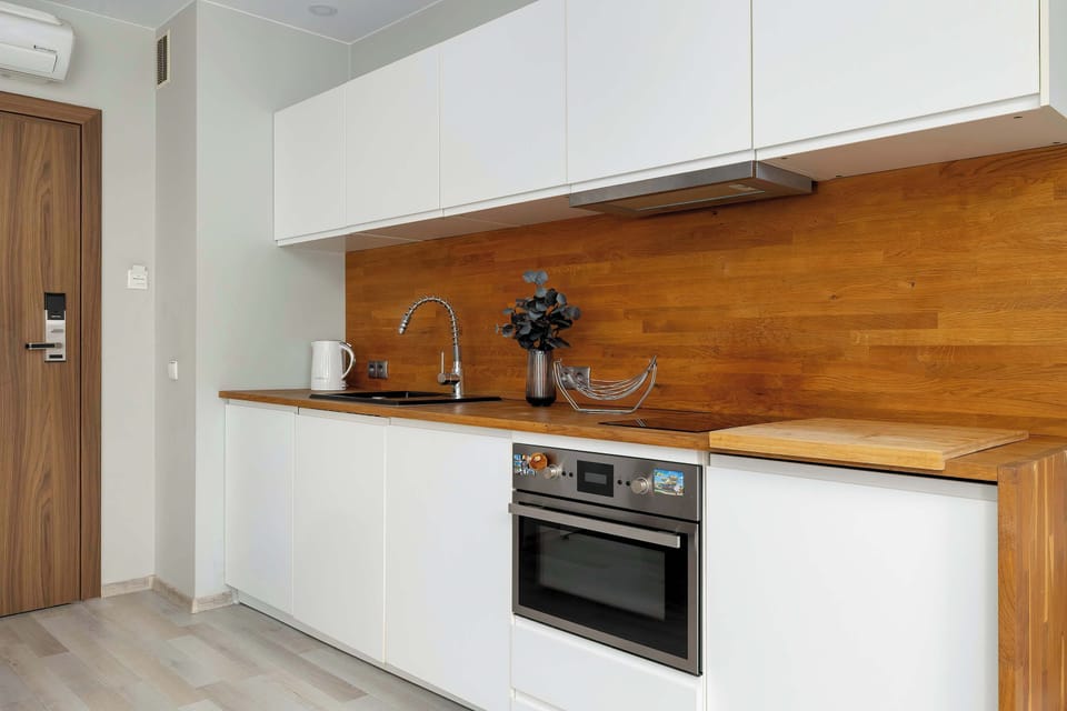A detailed view of the kitchenette focuses on the high-quality wood finish of the backsplash and the functional arrangement of the sink and stove. A modern coffee machine sits ready for use on the countertop.