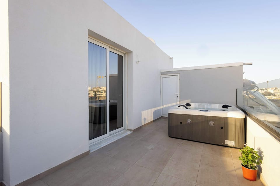Private balcony featuring a jacuzzi and a serene outdoor setting