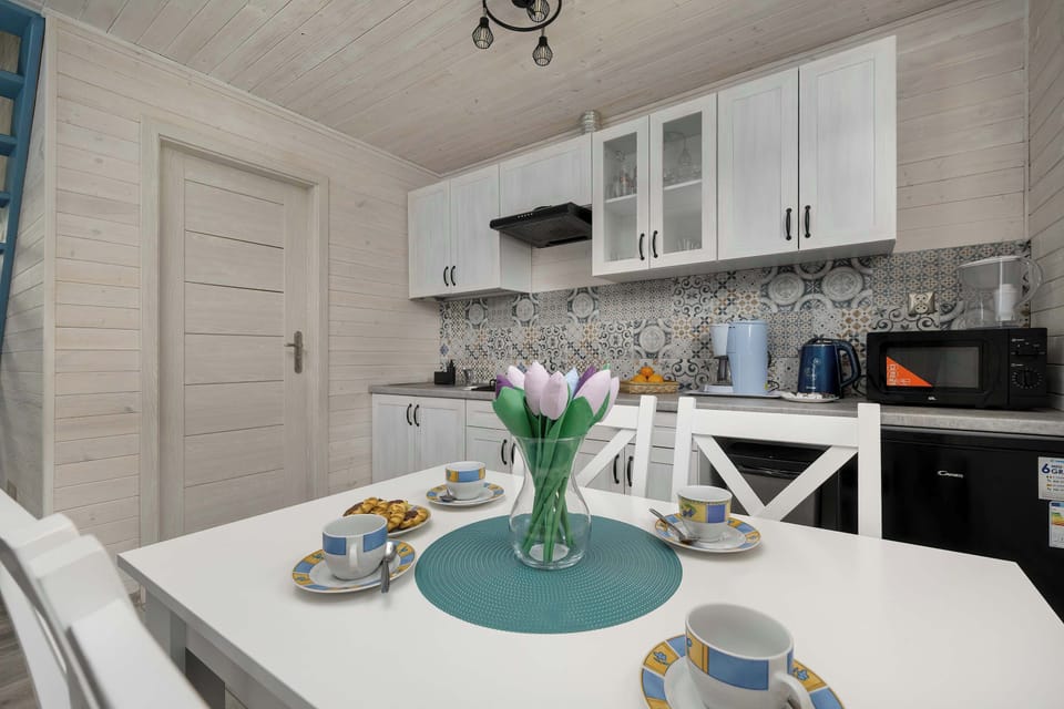 A closer look at the kitchenette and dining setup, highlighting clean countertops and a tidy cooking space. Decorative table settings add a welcoming and homely feel.