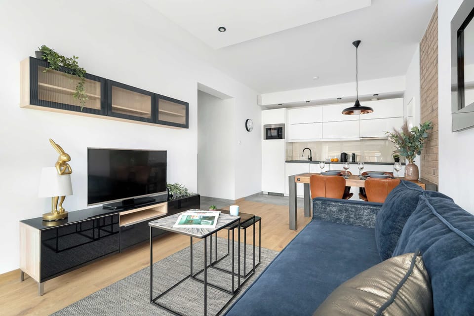 This perspective of the living area highlights a black media console sitting below a wall-mounted television. Natural light spills across the room, illuminating the neutral decor and polished finishes.