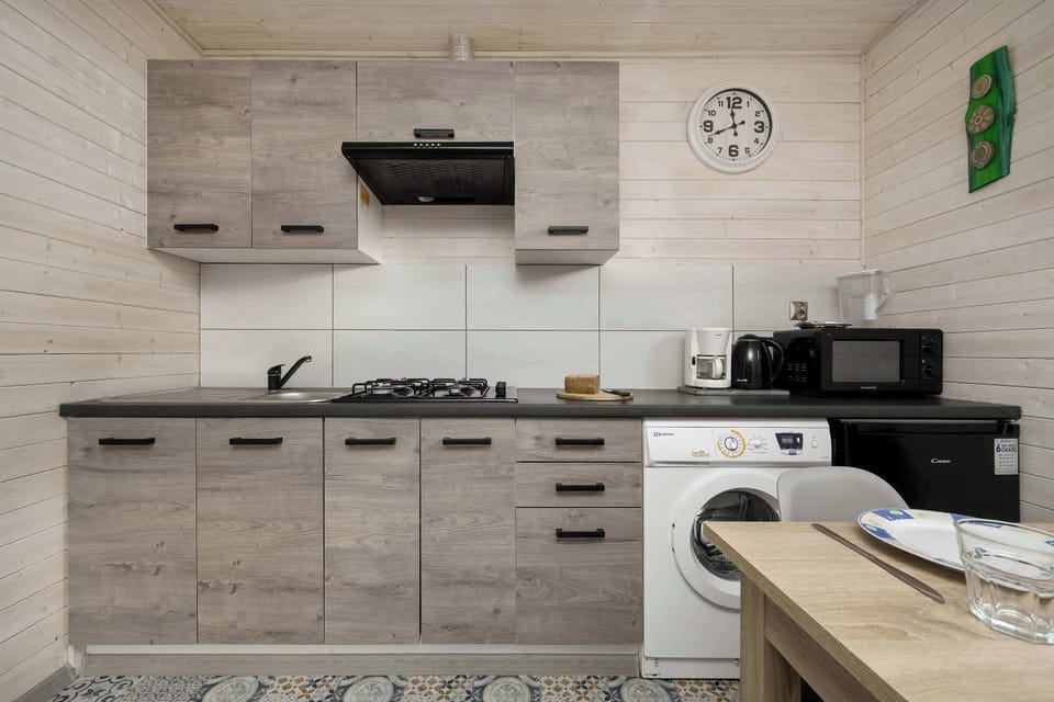 A kitchenette view with stove, sink, and upper cabinets. Soft lighting adds a modern touch.