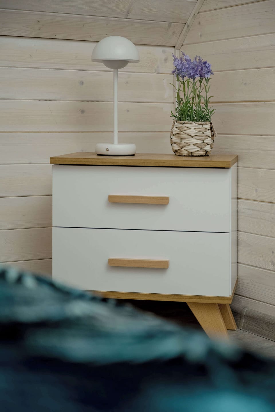 A bedside table with a lamp and small decor. Calm and уютny corner for rest.