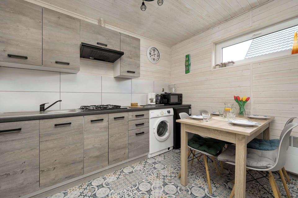 A compact kitchenette with wooden cabinets and a small dining space. Clean and functional layout.