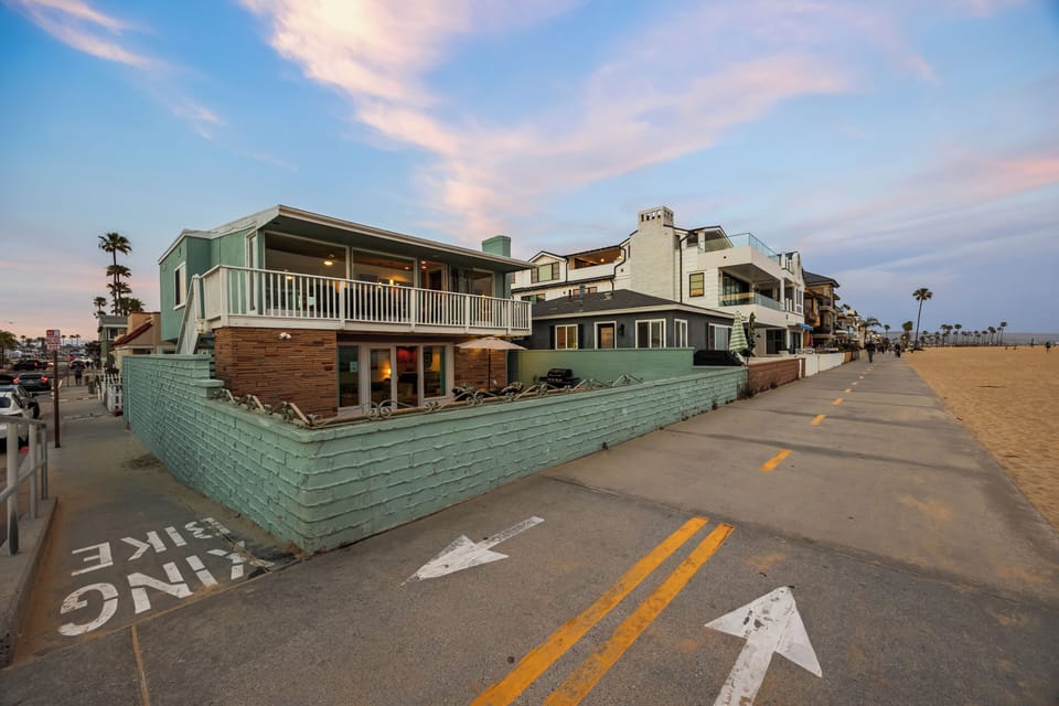 Step out your front door directly onto the world-famous Newport Beach boardwalk. This street-level shot showcases how close you are to the sand, the bike path, and the energy of the coastal community.