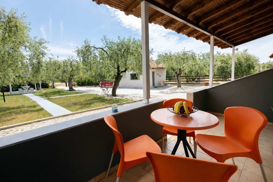 Bright and inviting private terrace with outdoor dining set, overlooking lush gardens and olive trees—perfect for relaxing mornings or sunset meals in a peaceful, natural setting.