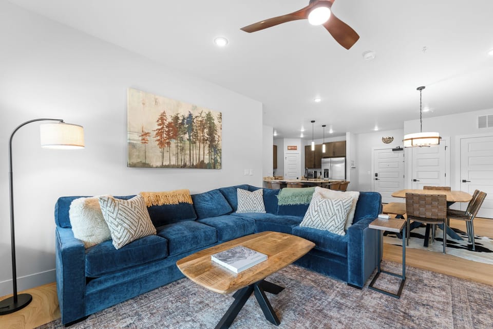 Settle into your inviting living space with a plush sectional and modern decor, where natural light and open flow connect you to the dining area and kitchen.