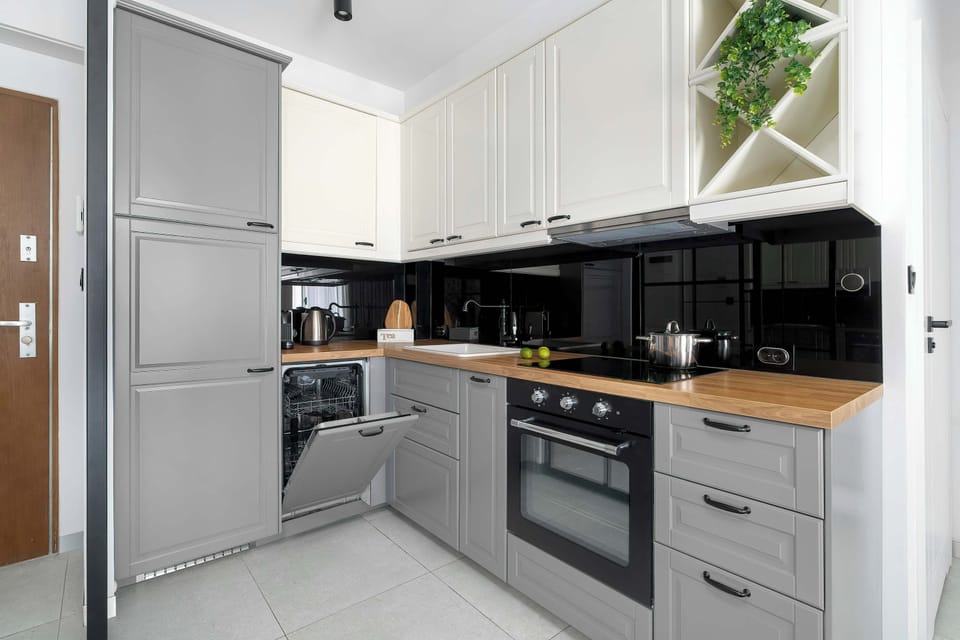 The kitchen is shown from an angle that highlights the built-in oven and the efficient organization of the grey cabinetry.