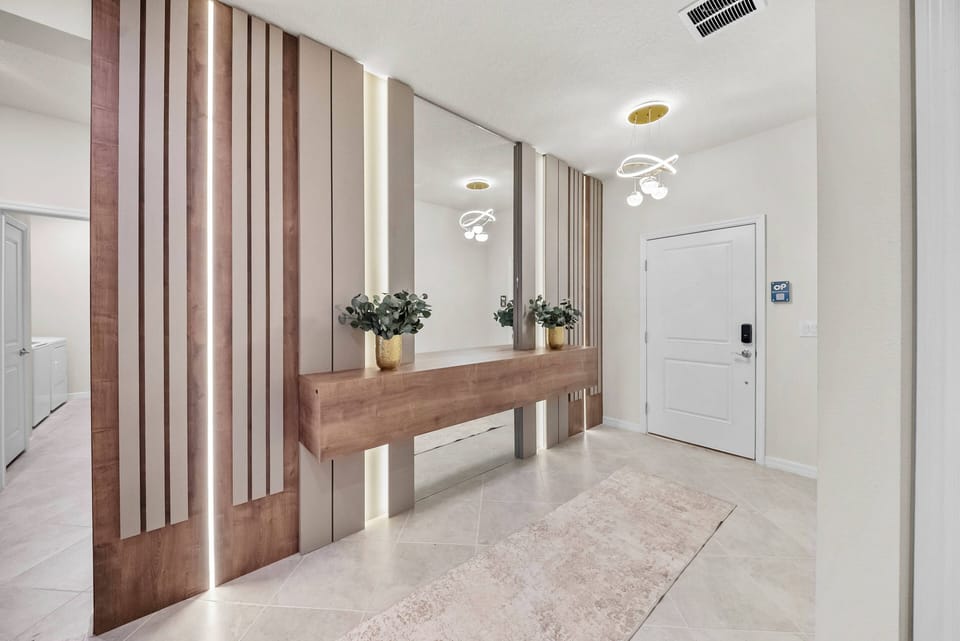 Welcome to a stylish entryway with warm wood accents and soft ambient lighting that instantly feels inviting. The sleek console table contrasts beautifully with the light tile flooring, providing an ideal spot for your essentials.