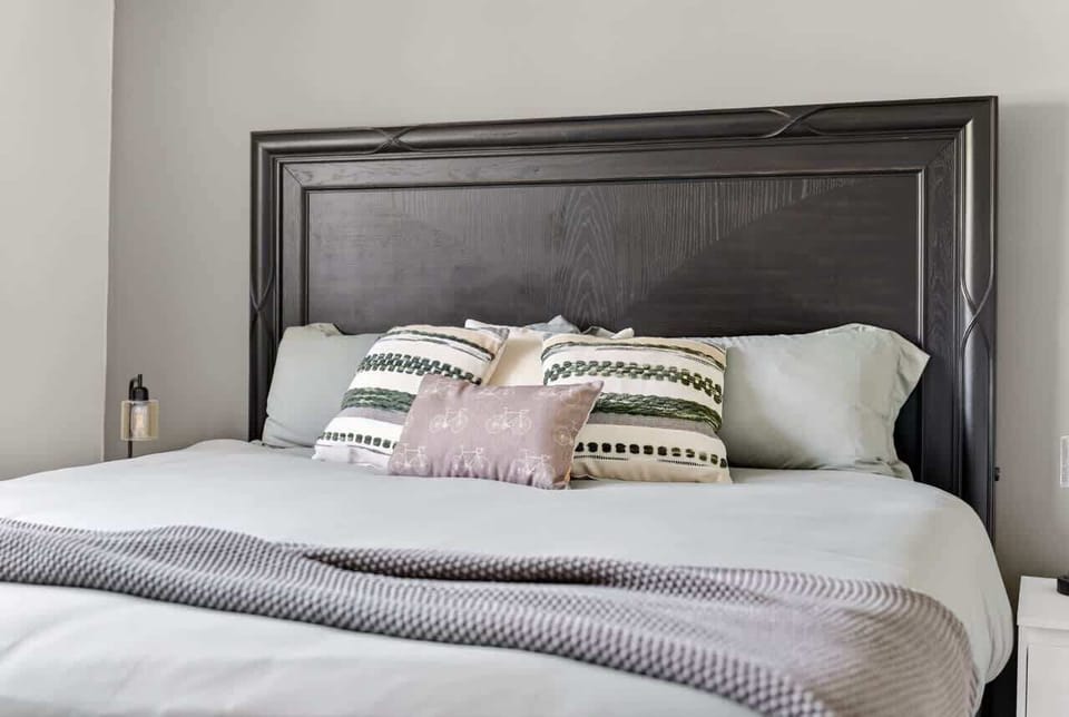 King bed with designer bedding and layered throw — bright, quiet retreat