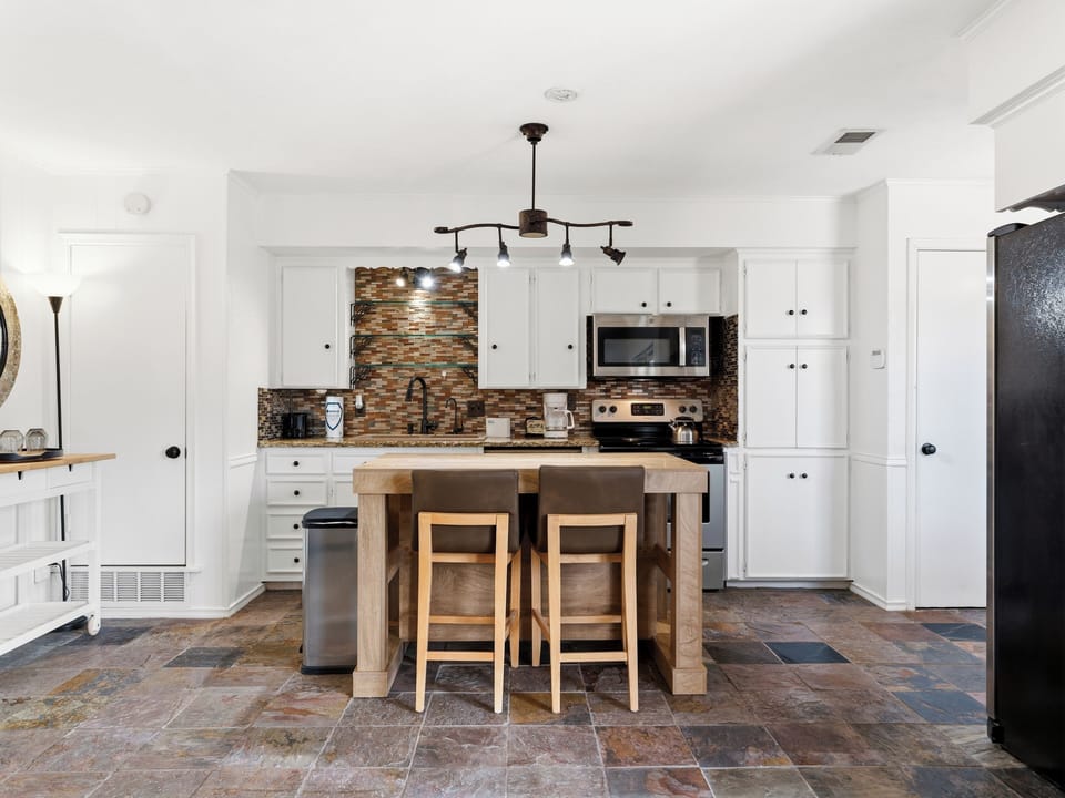 Your fully equipped kitchen blends modern convenience with rustic charm, featuring warm wood tones, granite countertops, and a cozy island perfect for morning coffee or meal prep.