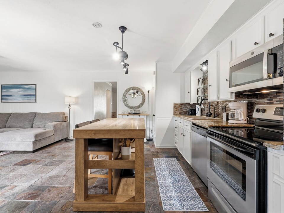 Your bright, open-plan living space combines comfort and style, with a well-equipped kitchen, cozy sofa, and warm wood finishes inviting you to cook, relax, and unwind.