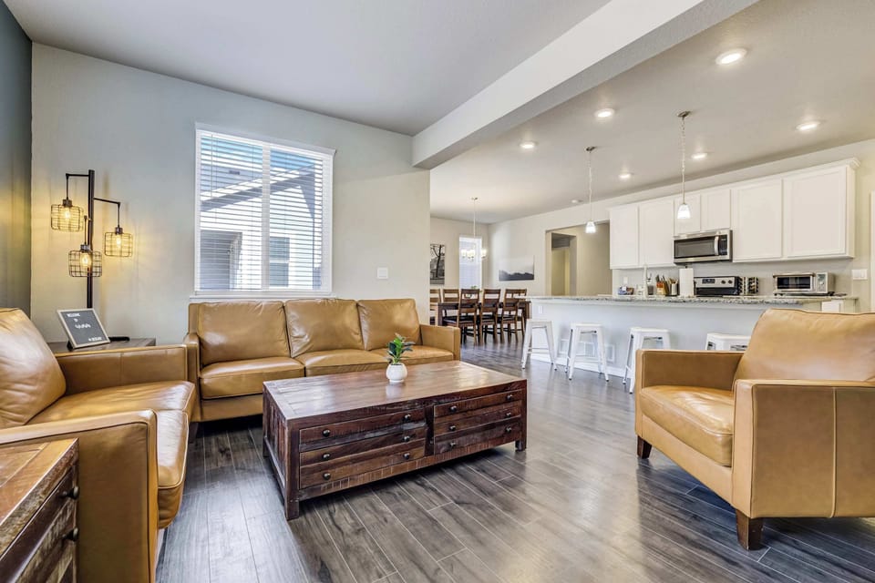 A wider view captures how the living area, dining space, and kitchen flow together across the main level. Recessed lighting, hardwood floors, and white cabinetry create a cohesive, well-lit environment throughout.
