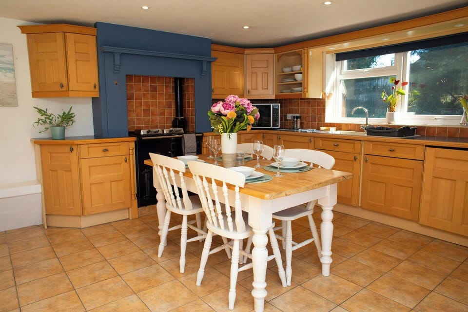 Kitchen with wooden cabinets, tiled floor, and dining table with four chairs