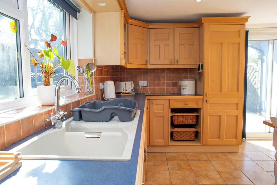 Sunlit kitchen with wooden cabinets, blue worktop and sink by a window