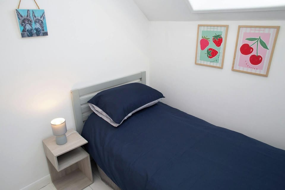 Bed with blue bedding and grey headboard next to small lamp