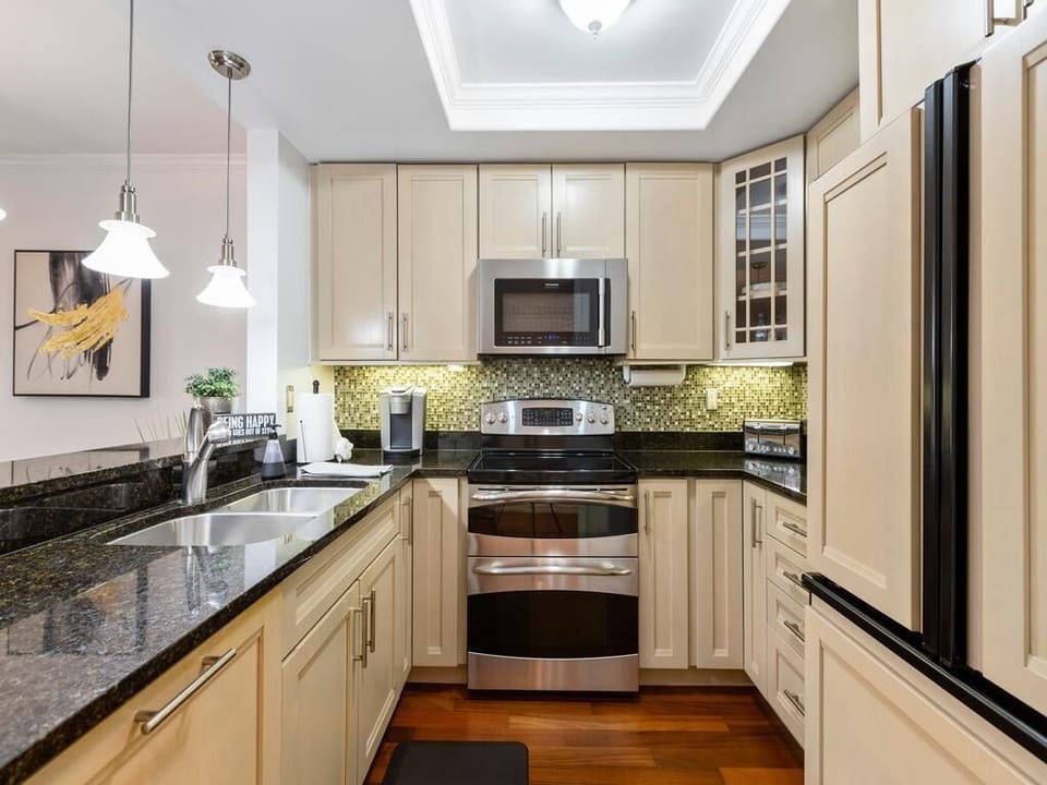 Granite countertops contrast with cream cabinets and mosaic tile backsplash in the kitchen.