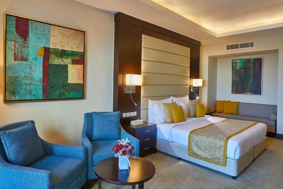 Relax in a plush bed beside a cozy lounge seating area.