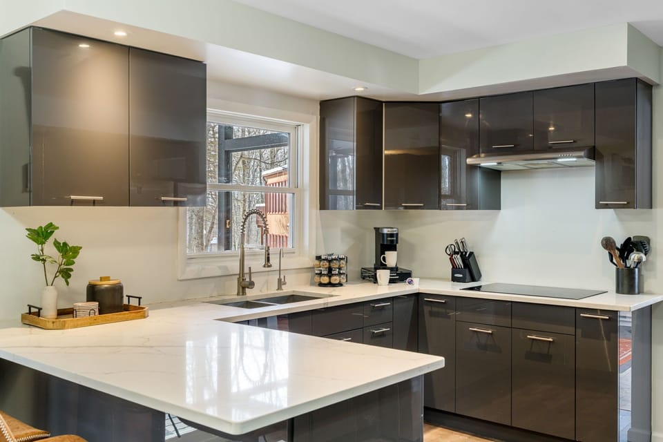 Modern kitchen with coffee station, large island, and wooded views.