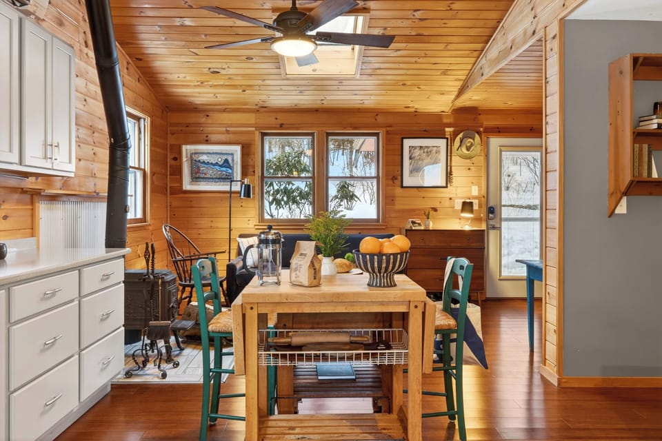 Open kitchen and living space with a central prep island, wood-burning stove, and natural light—easy for cooking, gathering, and everyday cabin living.