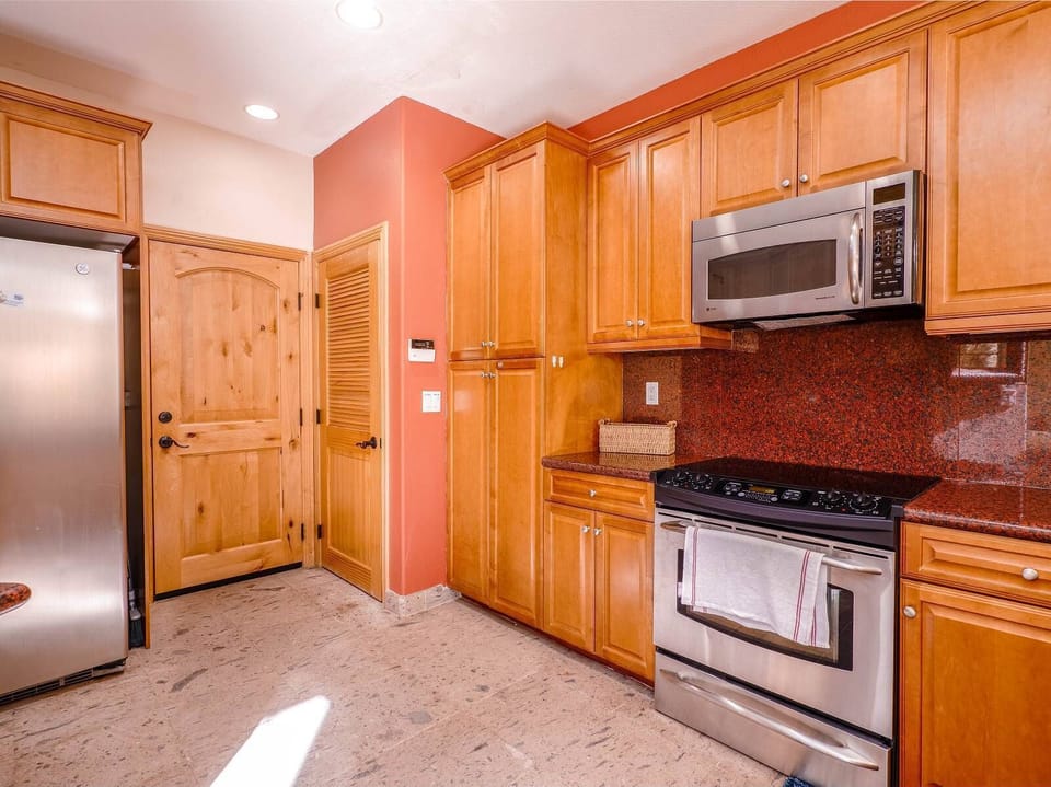 The kitchen at Condo 114 includes a full-size refrigerator, oven, microwave, and essential cookware — everything needed to prepare meals while enjoying access to community pools and the private beach.
