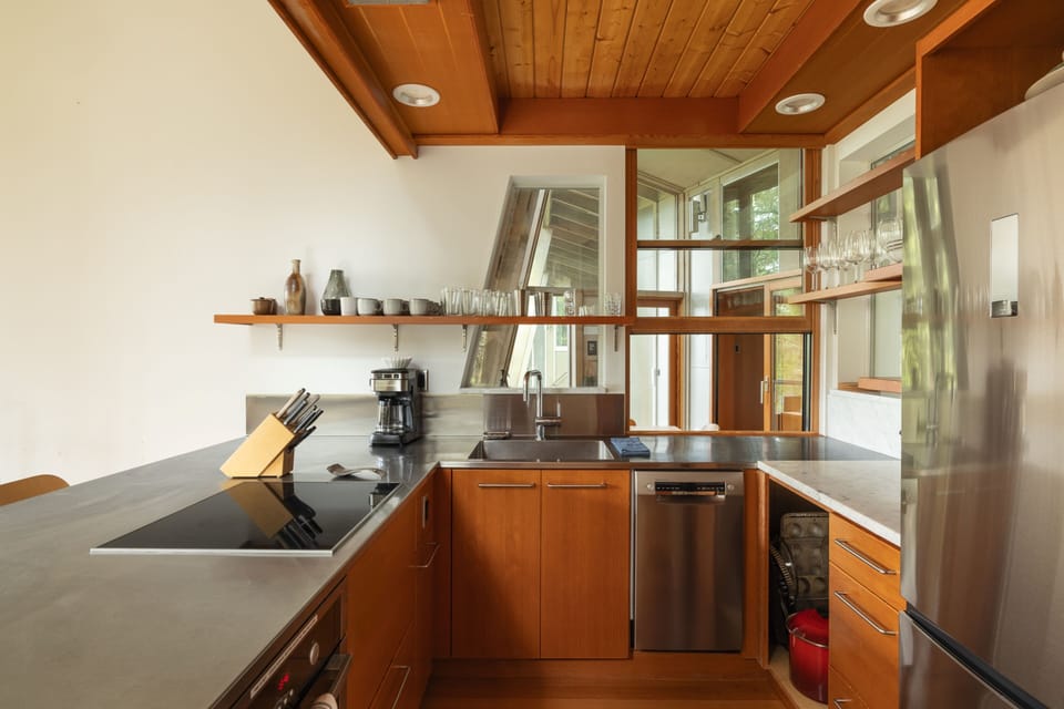 Your sleek modern kitchen features warm wood cabinetry, granite countertops, and stainless appliances with natural light streaming through large windows.