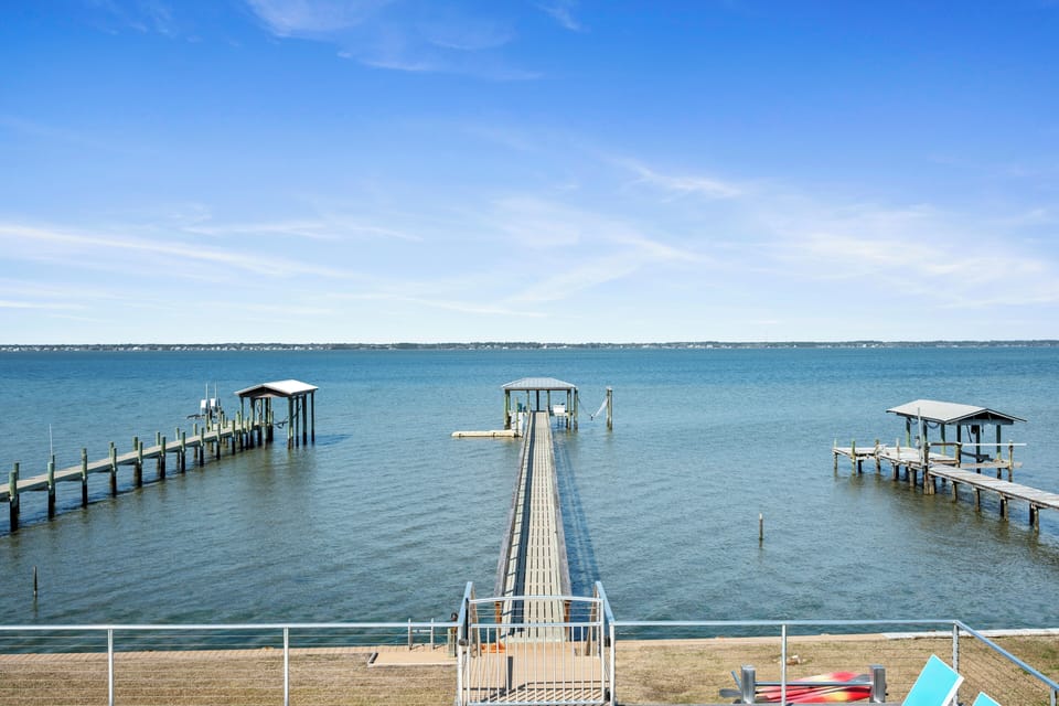 Scenic waterfront location featuring multiple private docks extending into calm blue waters under expansive skies.